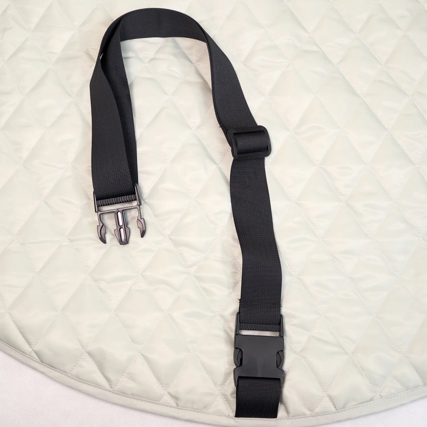 Close-up detail of the black adjustable clip strap resting on the quilted interior playmat surface.