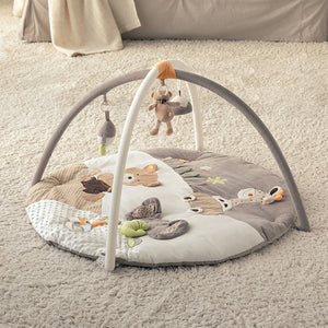 A round minidream baby play mat with safari-themed animals and a frame with hanging toys, set on a carpeted room.
