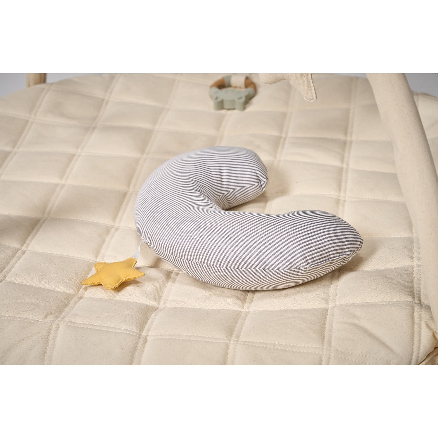 Striped body tummy time pillow on a beige quilt with a yellow star