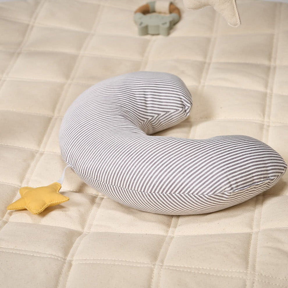 Striped body tummy time pillow on a beige quilt with a yellow star
