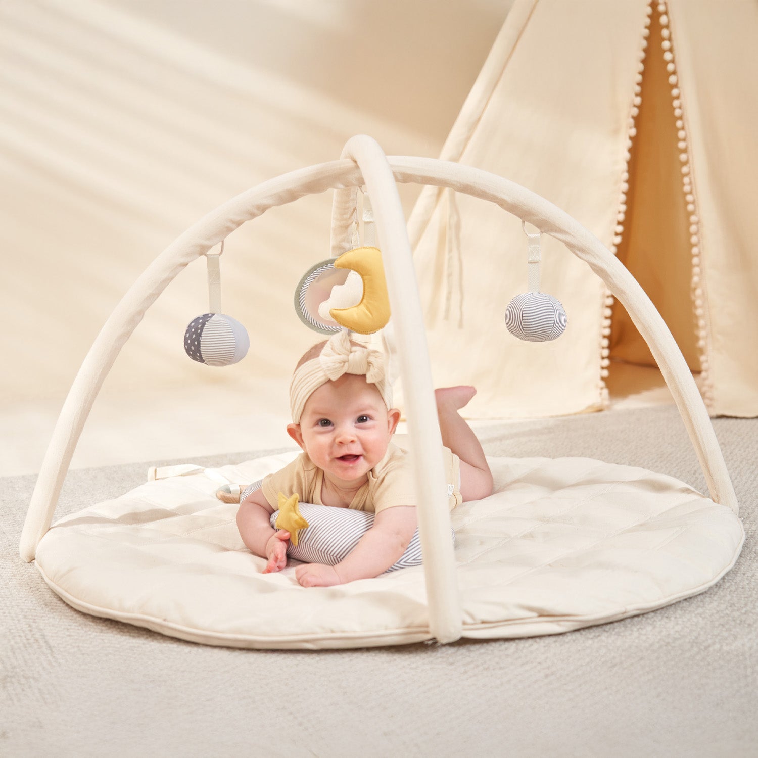 Baby playing with a minidream baby gym on a soft play mat