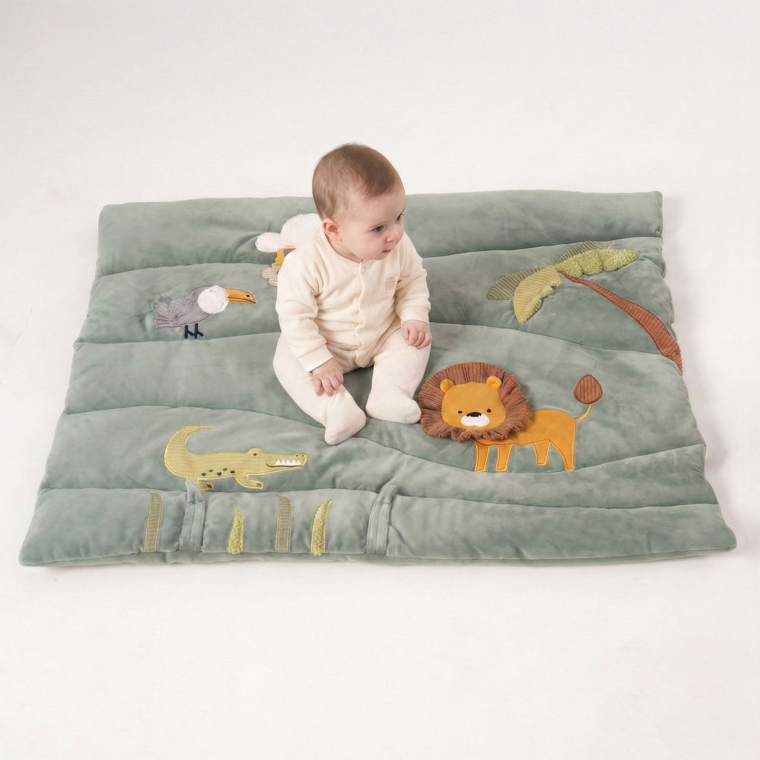 A baby is sitting one the MiniDream activity gym.