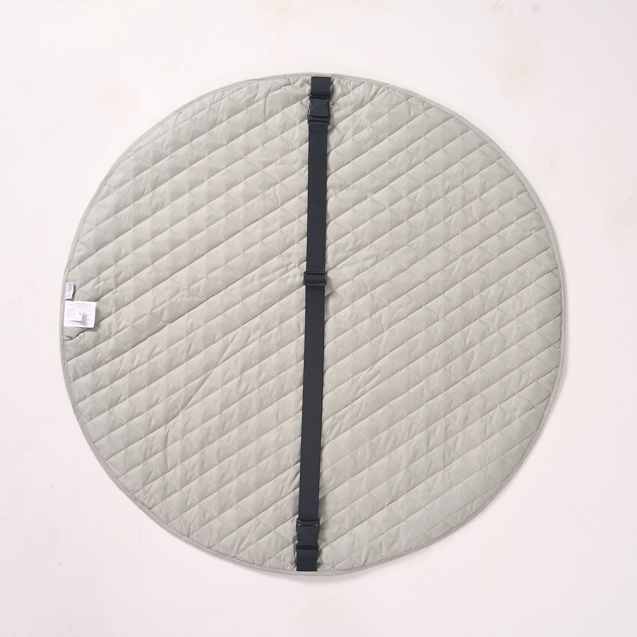 Solid light green reverse side of the playmat laid flat, featuring a black fabric strap running across the center.