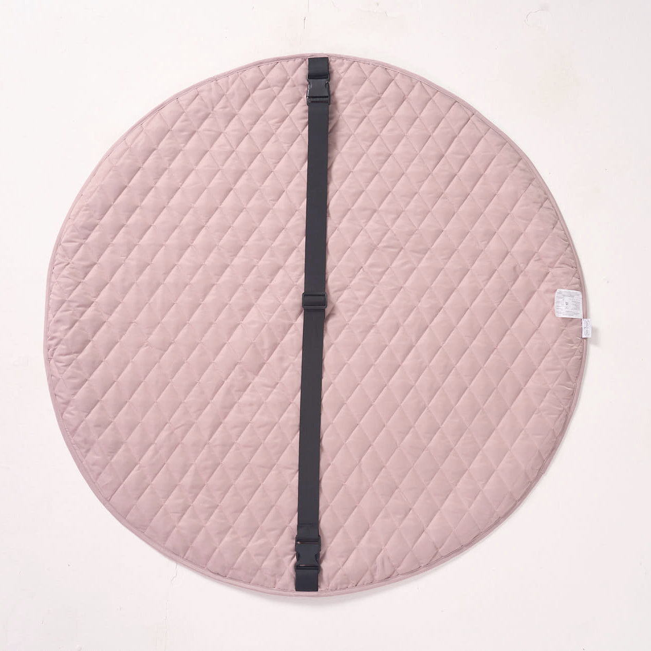Solid pink reverse side of the playmat laid flat, showing a black fabric strap running across the center.