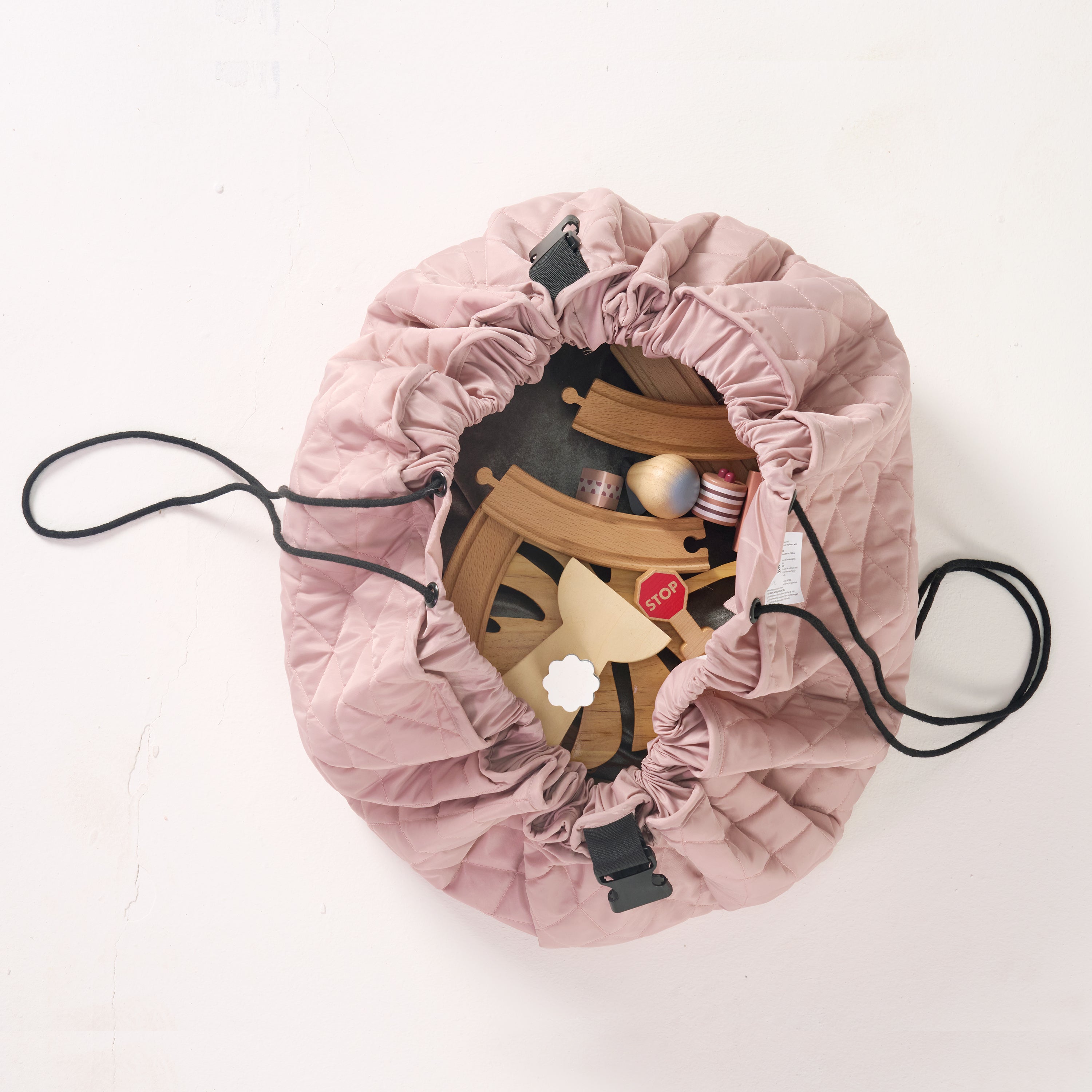Pink playmat partially cinched together into a bag, revealing wooden blocks inside.