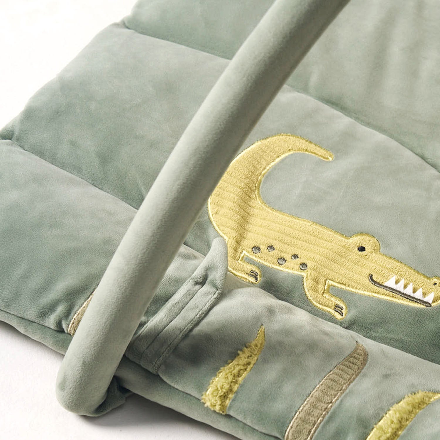 Green playpan with gold crocodile embroidery on a white background.