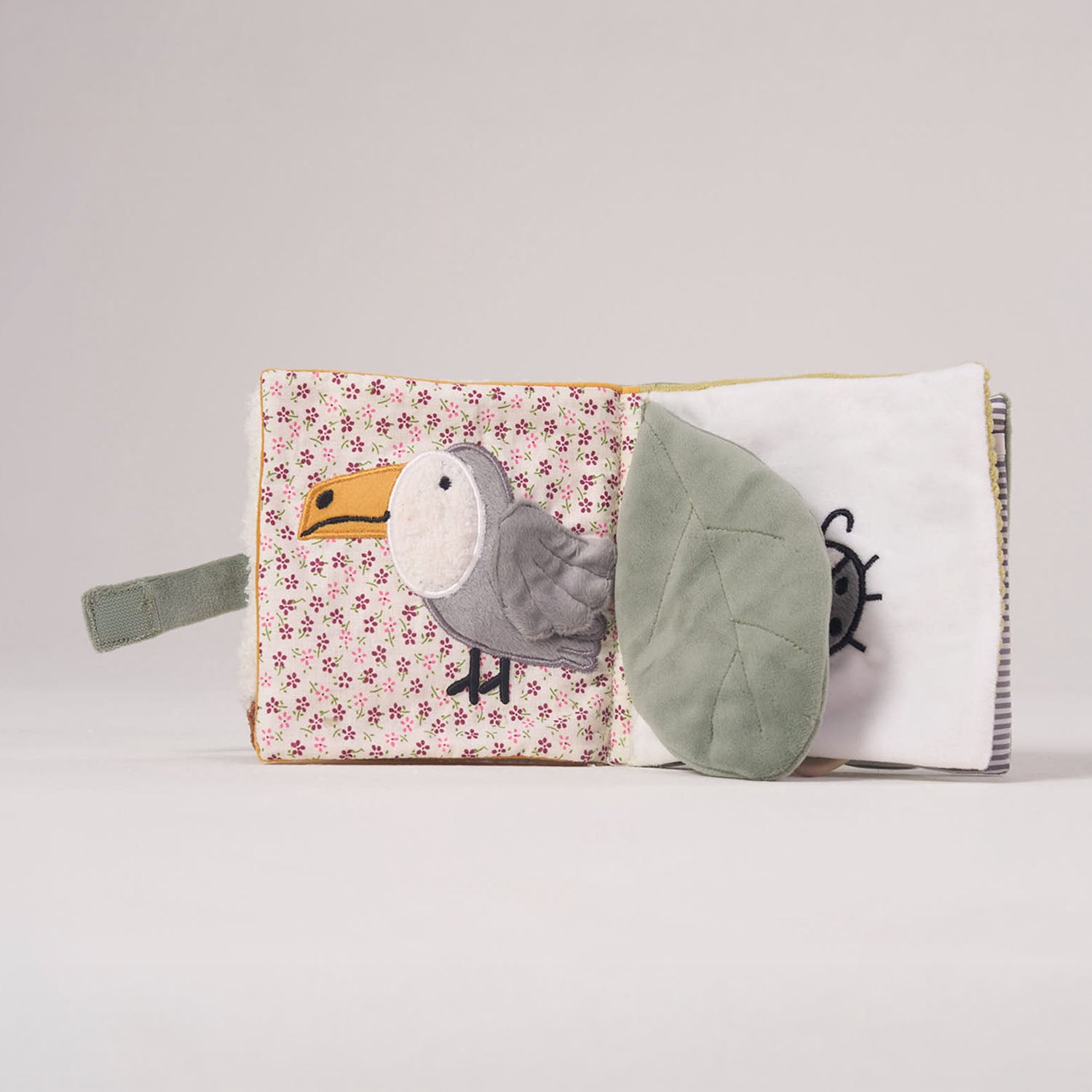 Inside spread of the MiniDream baby activity book showing a soft fabric toucan and crinkly leaves designed for early sensory development.