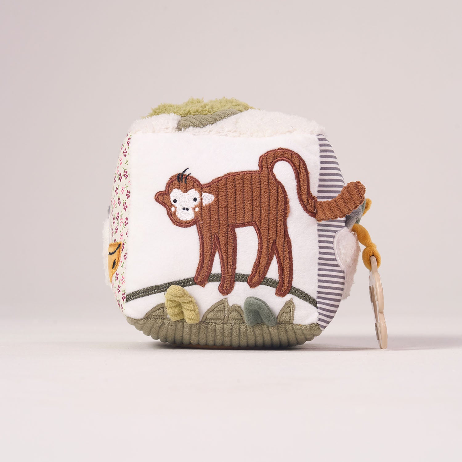 Soft textured side of the MiniDream baby activity toy showing a playful monkey swinging from a jungle branch.
