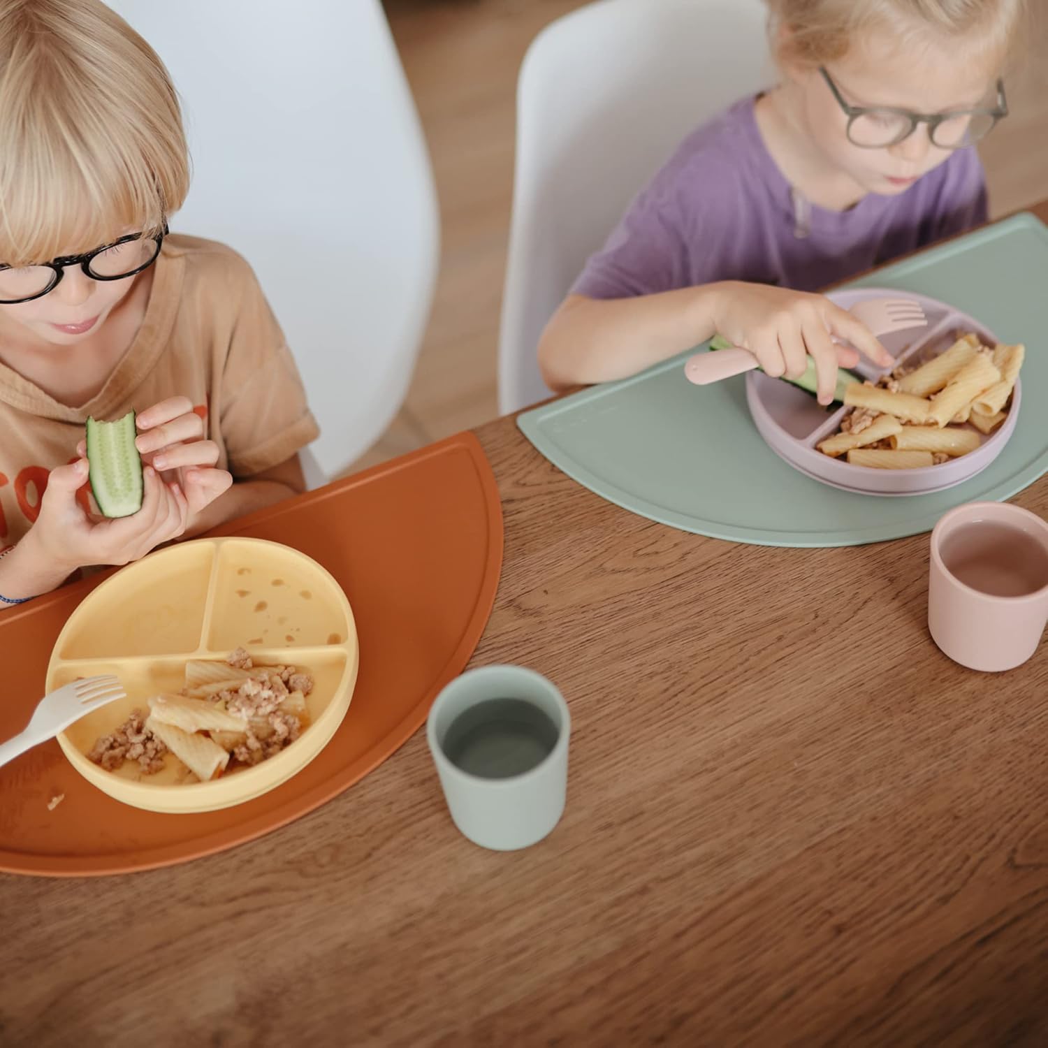 Kids are having food in mushie dinnerware cups and plates.