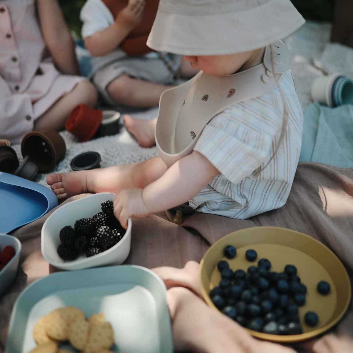 toddler is having fruits on mushie square plates.