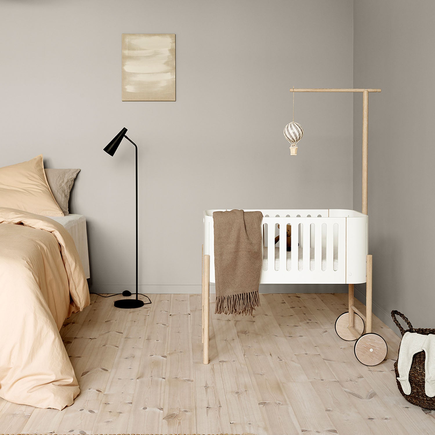Wooden holder mounted with soft mobile toys hanging in the co-sleeper.