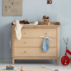 Nursery dresser with changing top and rounded edges in a modern baby room