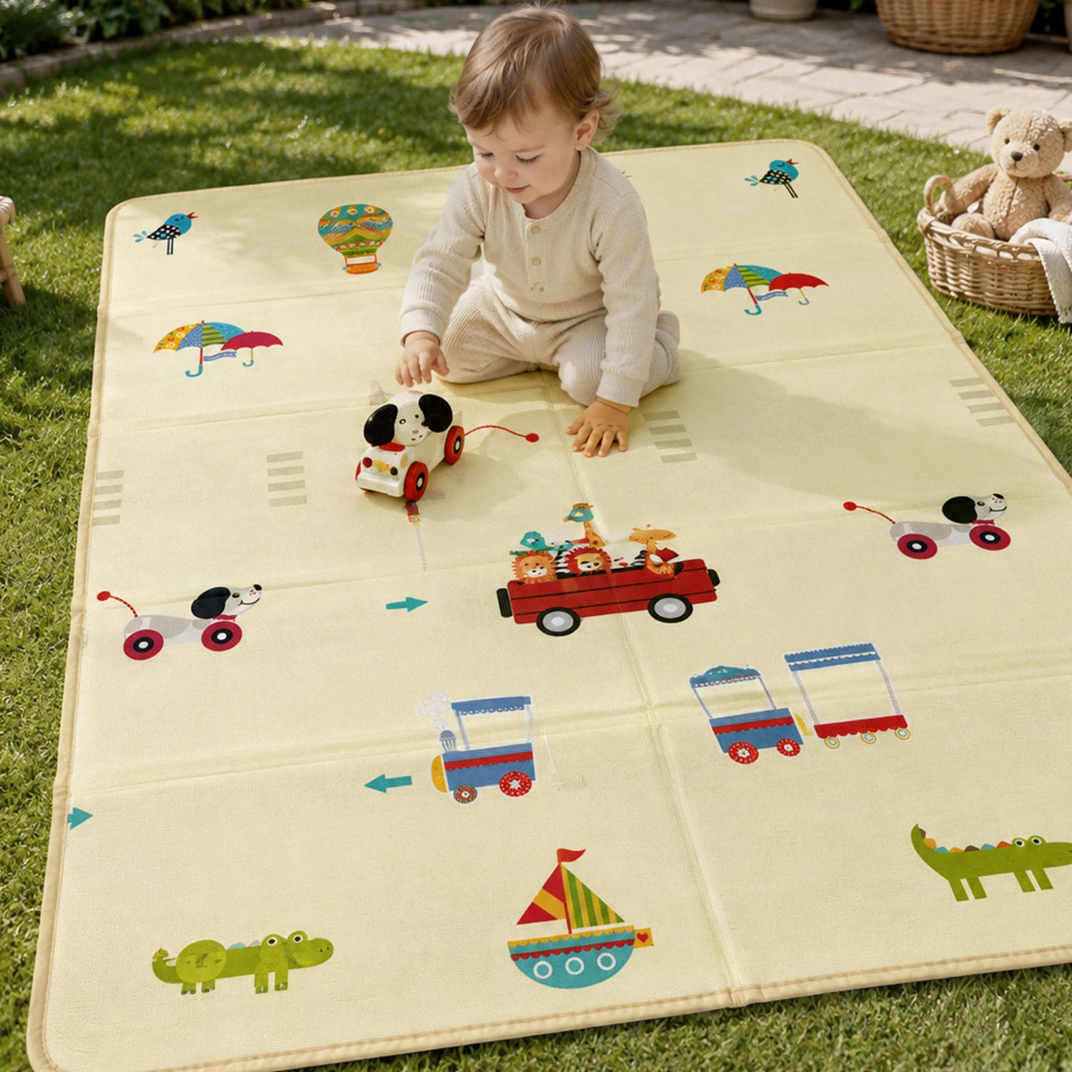 A baby playing happily with a toy on the vehicle-themed side of the Allis Folding Play Mat set up outdoors on a grassy lawn.