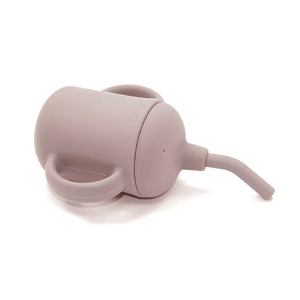 Blush pink silicone sippy cup with handles resting on its side.