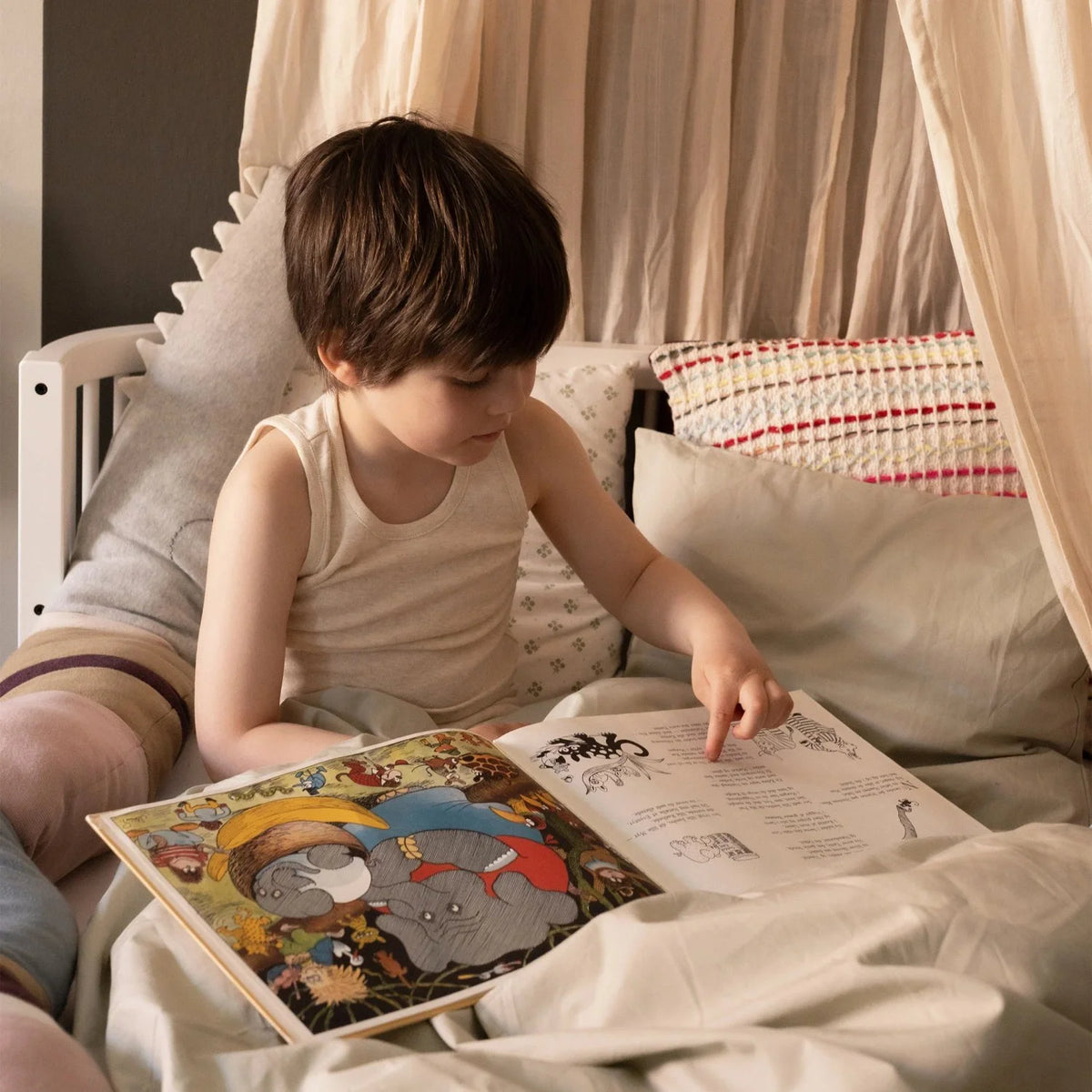 Young child reading and playing on Sebra Junior & Grow bed, demonstrating safe, spacious design for growing kids