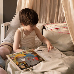 Young child reading and playing on Sebra Junior & Grow bed, demonstrating safe, spacious design for growing kids