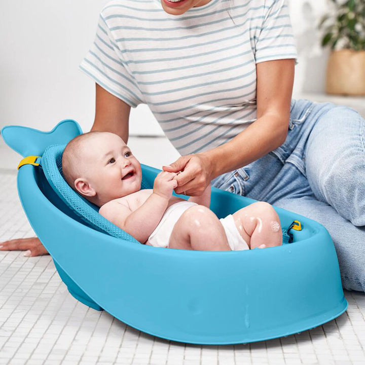Blue Skip Hop Moby 3-Stage Bathtub with baby in a seated position, supported by the sling.