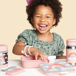 A girl is eating from Skip Hop lunch box