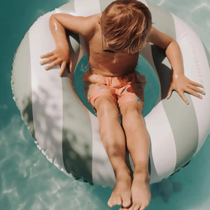 A toddler is having fun with the swim ring in the pool.