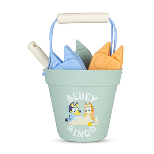 Bluey Swim Essentials silicone beach toy set featuring a blue bucket, shovel, and sand moulds in a mesh carry bag.