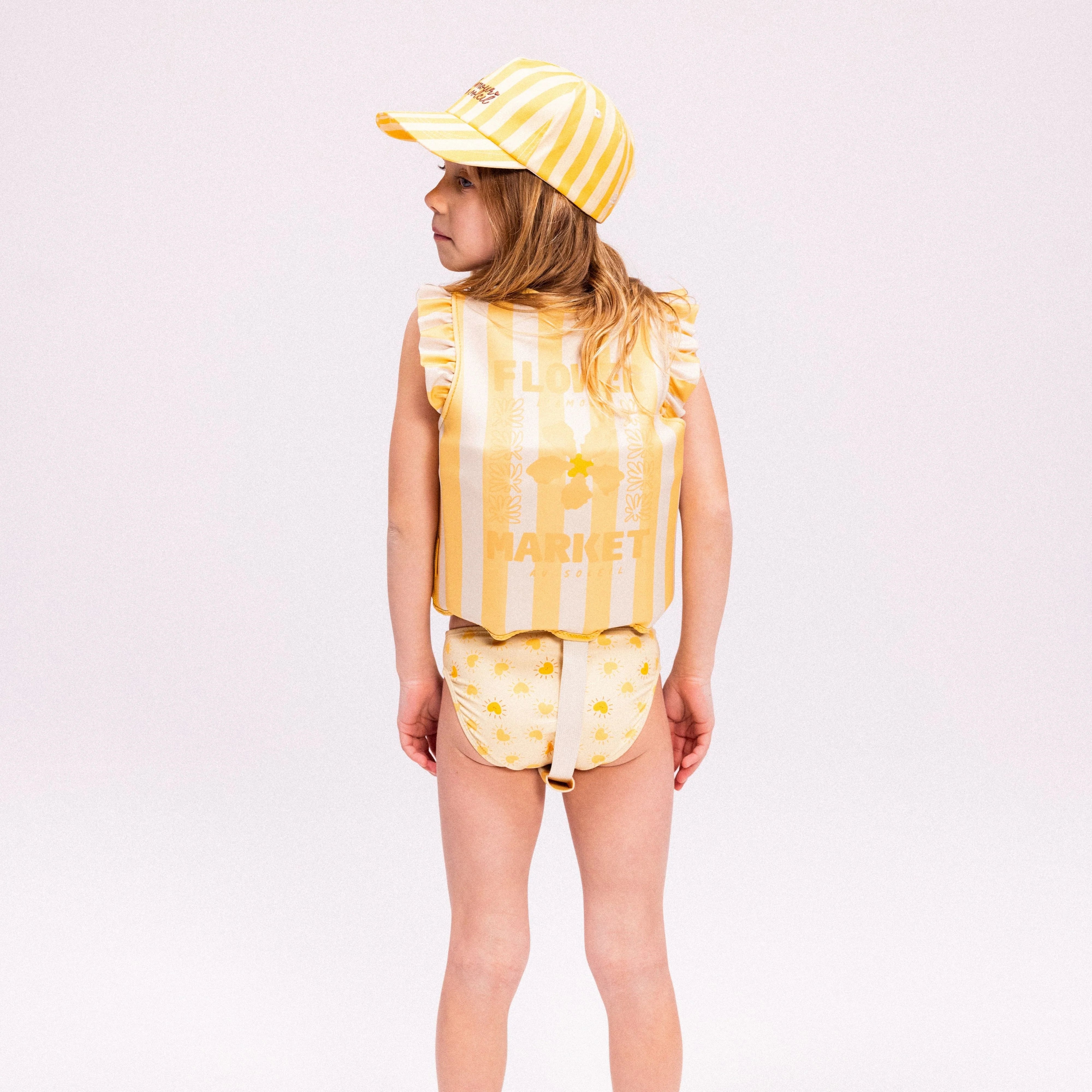 A young child wearing the floral swim vest.