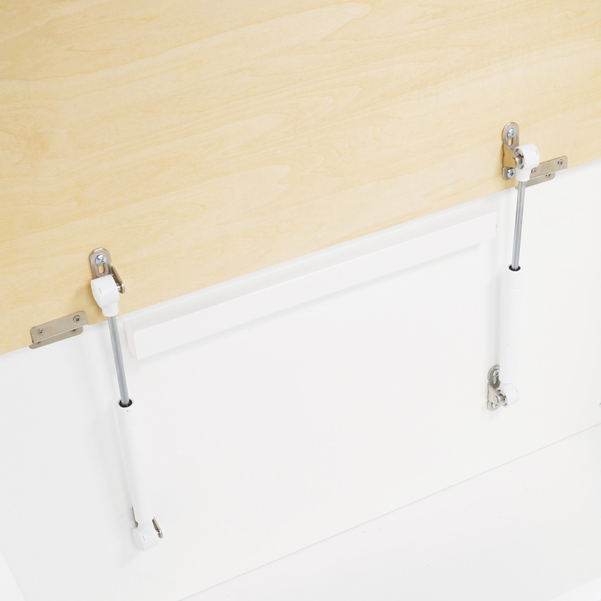 Metal bed railings on a white bed against a beige wall.
