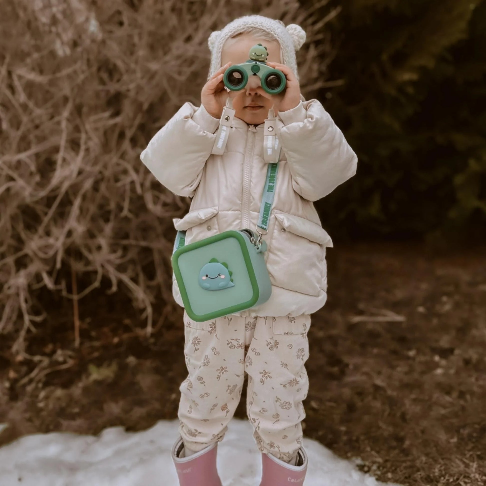 Girl enjoying playtime with zoo eyes dino binoculars.