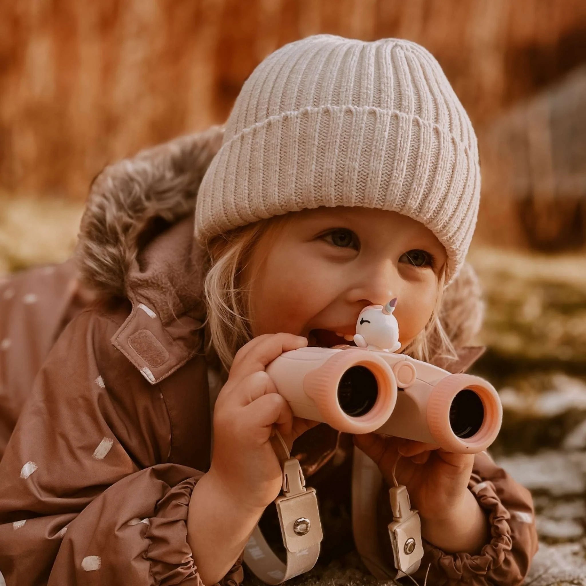 Girl smiling while using zoo eyes unicorn binoculars.