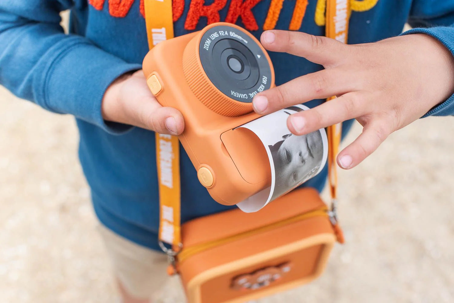 Child holding a toy camera with an orange and blue design