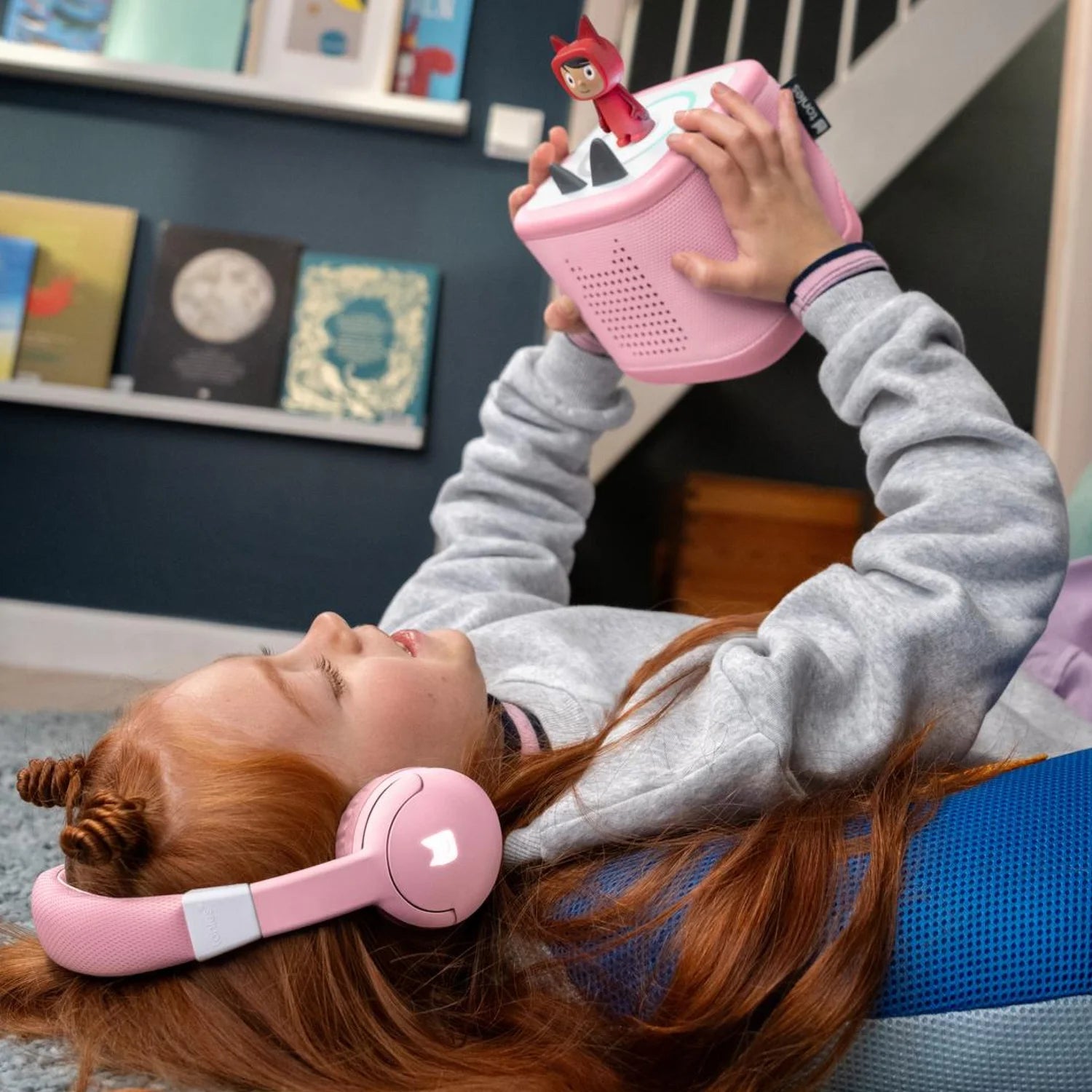 A girl is listening tonies story with Tonebox 2 pink bluetooth headphones.