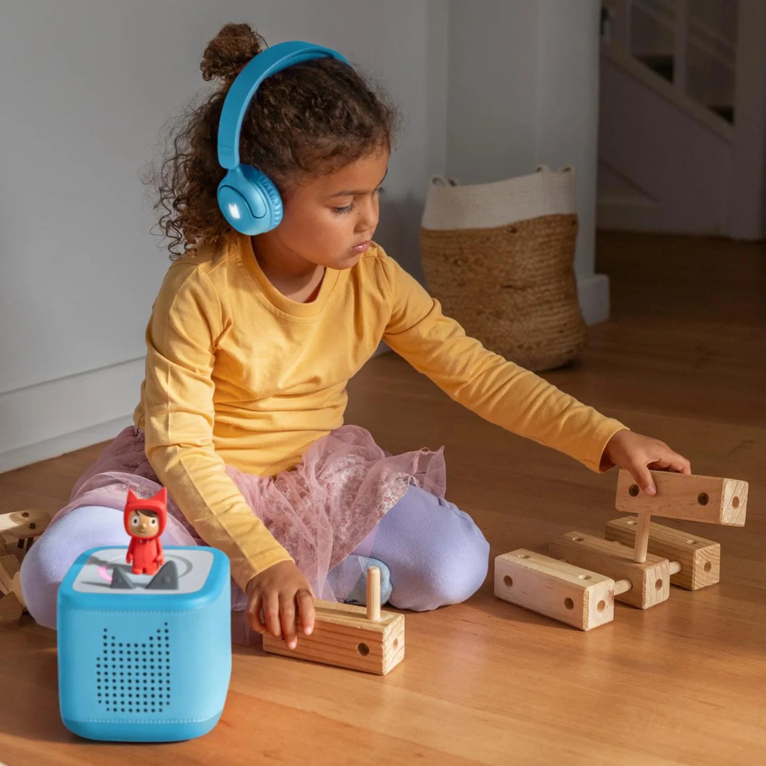 Child wearing toniebox 2 headphones and playing with a wooden toy.