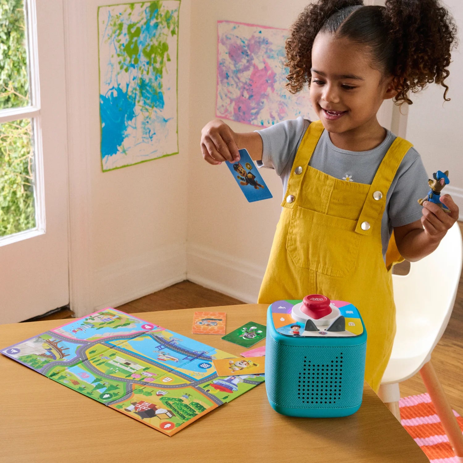 A girl is playing with the toniebox PAW patrol chase playset and tonieplay.