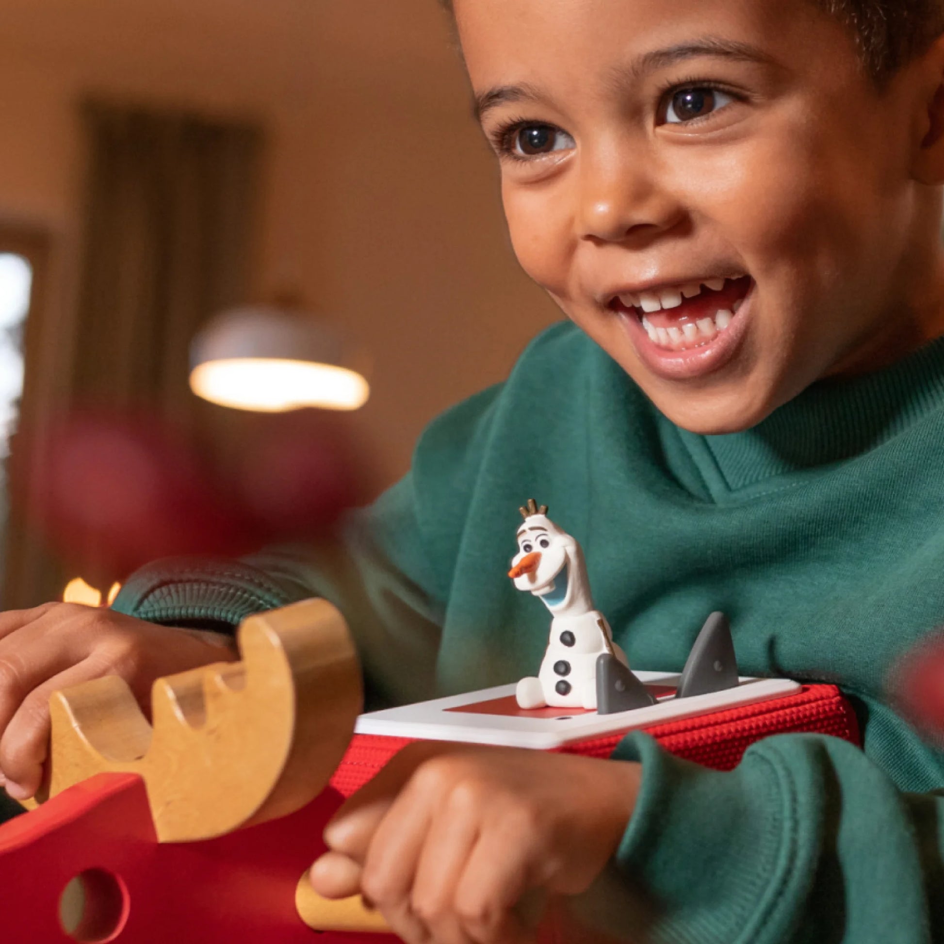 A young child sitting on a rug smiling while listening to the Olaf story.
