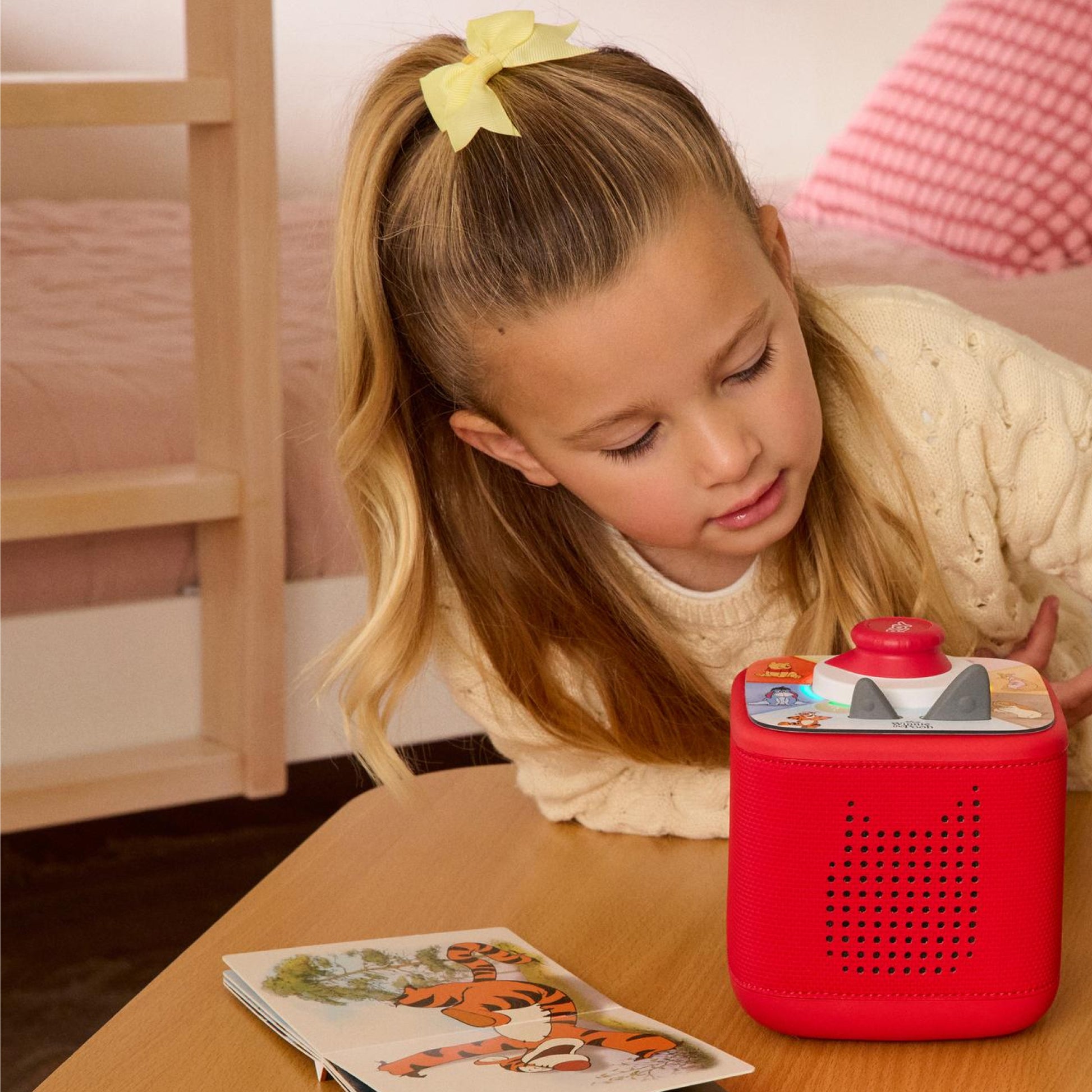 A girl is playing with Toniebox and Winnie the Pooh Tonieplay