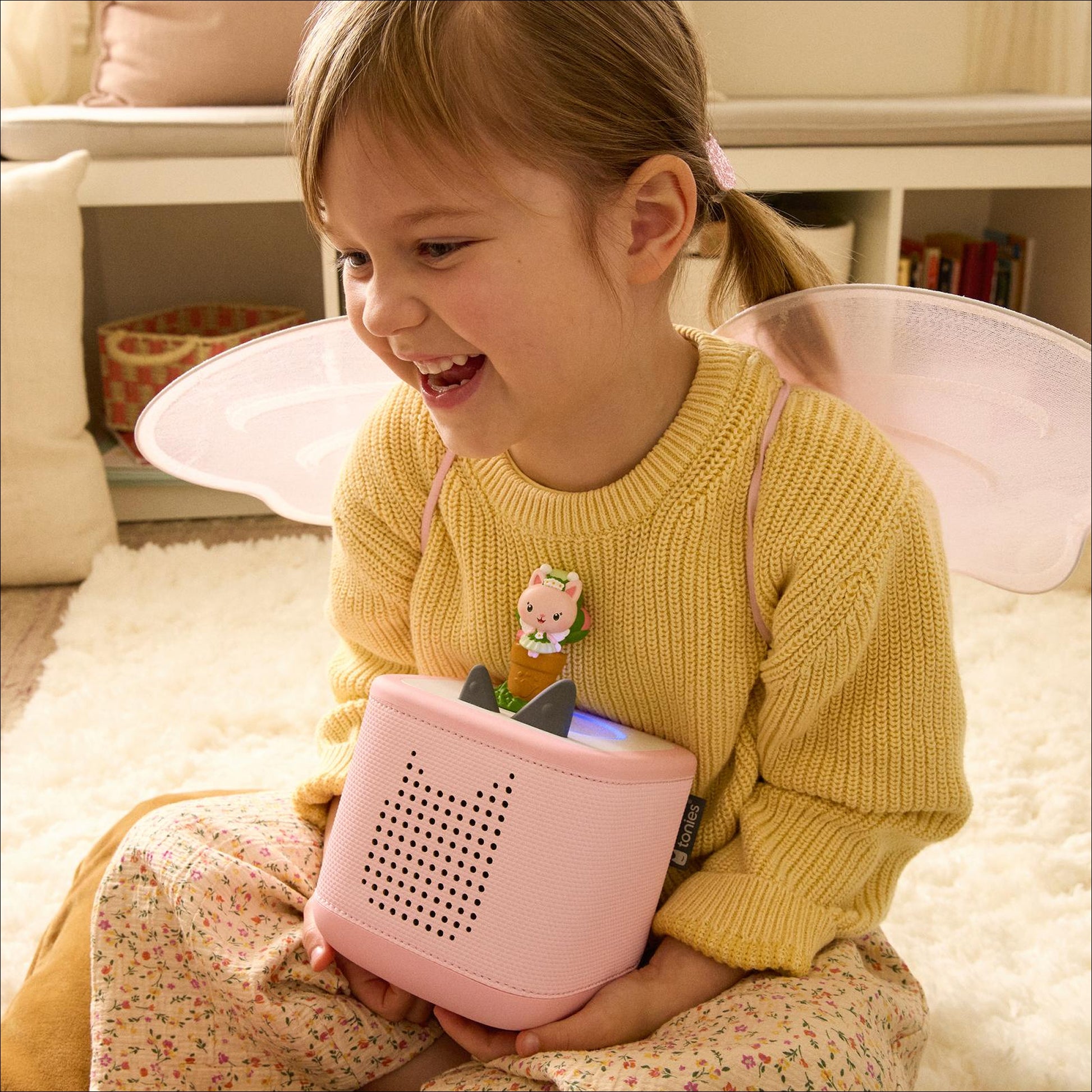 Child placing a Kitty Fairy character on top of a Toniebox audio player.