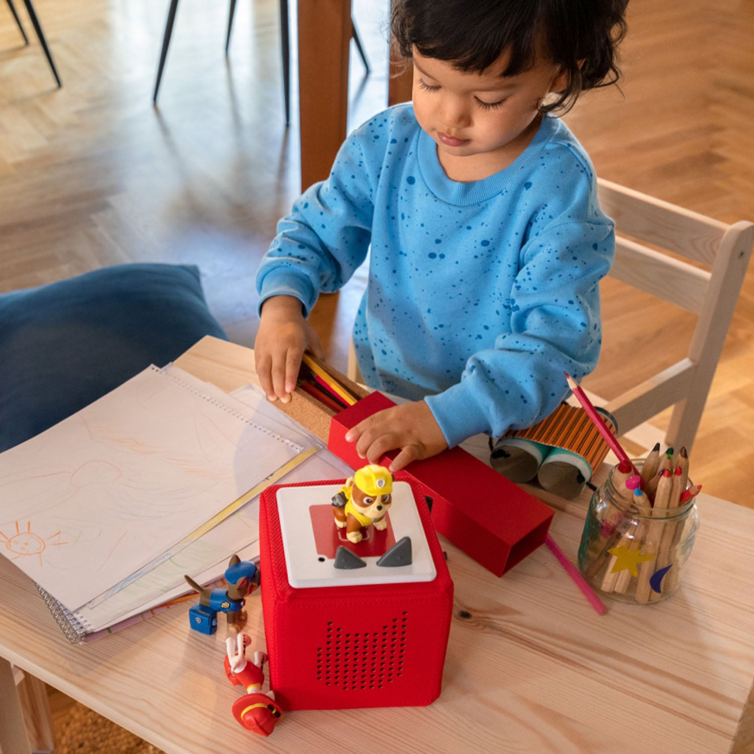 Child placing Rubble character on the audio player for screen-free play.