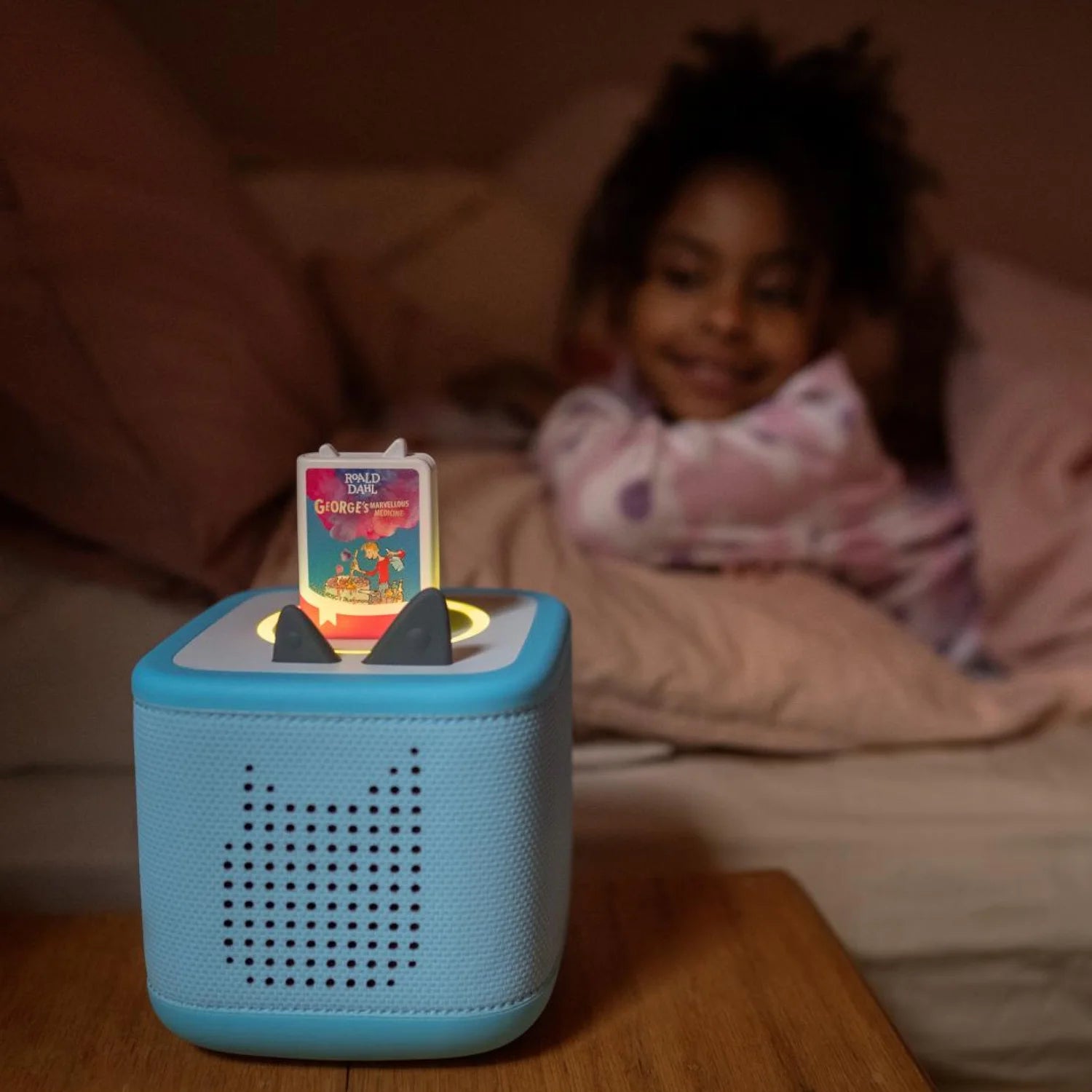 Child listening to George's Marvellous Medicine on a Toniebox in a cozy bedroom.
