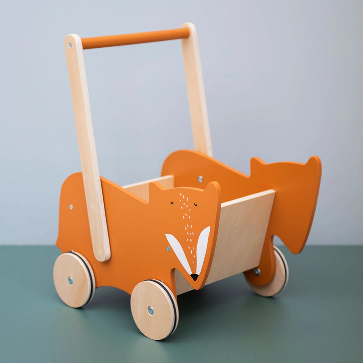 The Trixie Wooden Push Along Cart - Mr. Fox parked in a child's playroom with toys scattered around it.