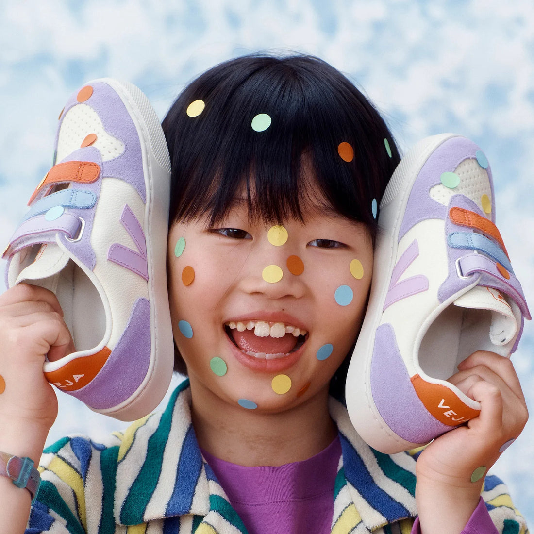 A kids is having fun with the veja v-10 kids leather sneakers.