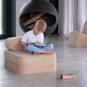 A boy is reading a book sitting on the Wigiwama foldable chair.