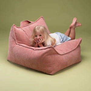 A toddler is lying on the beanbag.