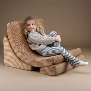 A toddler is sitting on the moon-shaped chair.