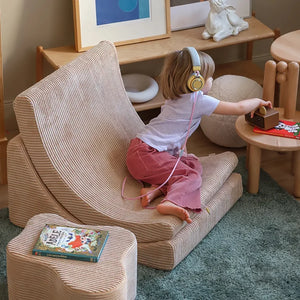 A toddler is relaxing and listening song in the soft chair.
