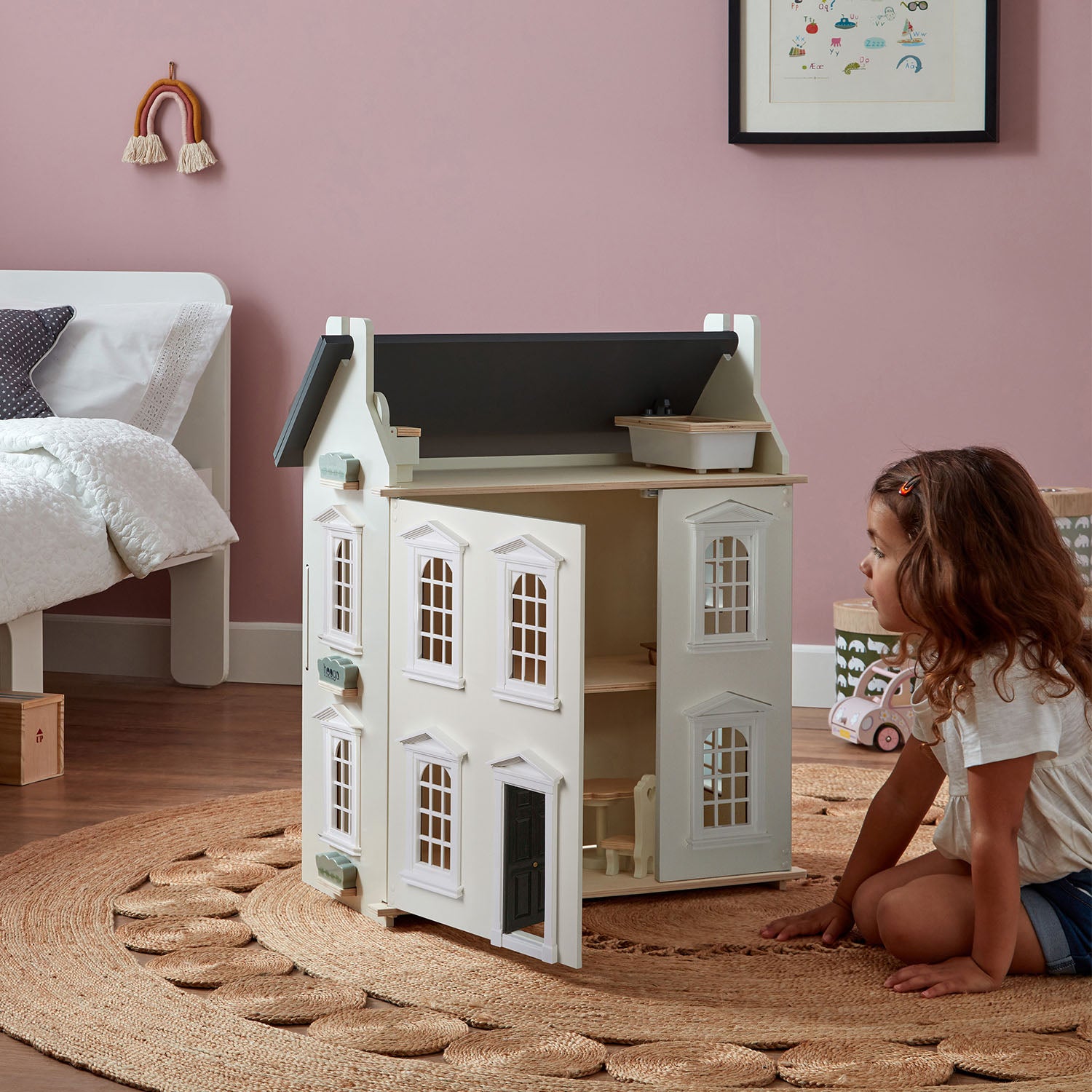 A girl is playing with hooga, wooden doll houses.