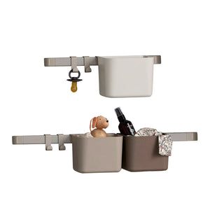 Two storage baskets hanging on a white wall, above a changing table. The baskets are filled with baby supplies, including a pacifier, a bottle of lotion, and a teddy bear.