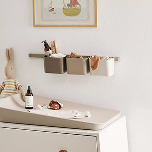 A close-up of a changing table with baby supplies on it, including a bottle, brush, and socks