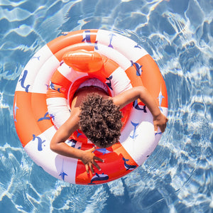 A smiling kids enjoying a sunny day in the pool, safely supported by the Swim Essentials Whale Baby Float