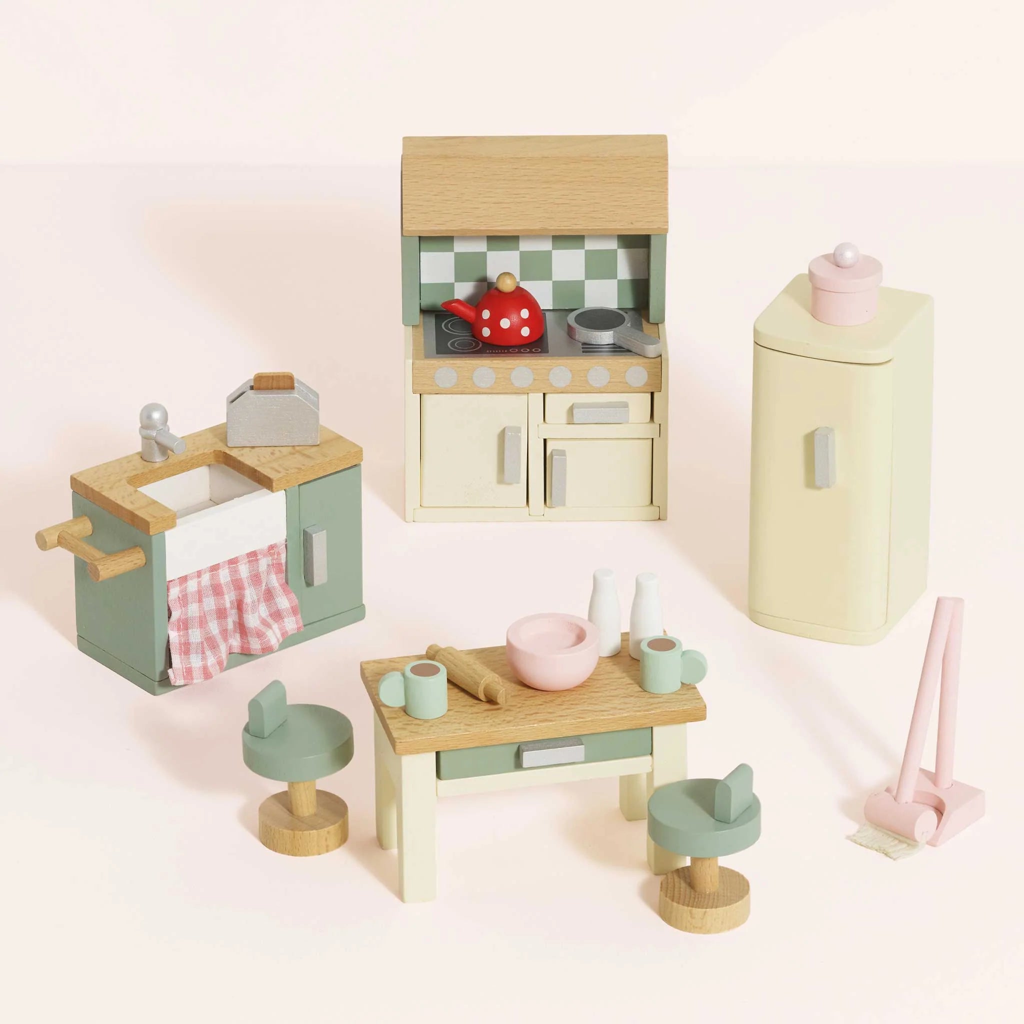 Set of wooden toy kitchen furniture on a light pink background