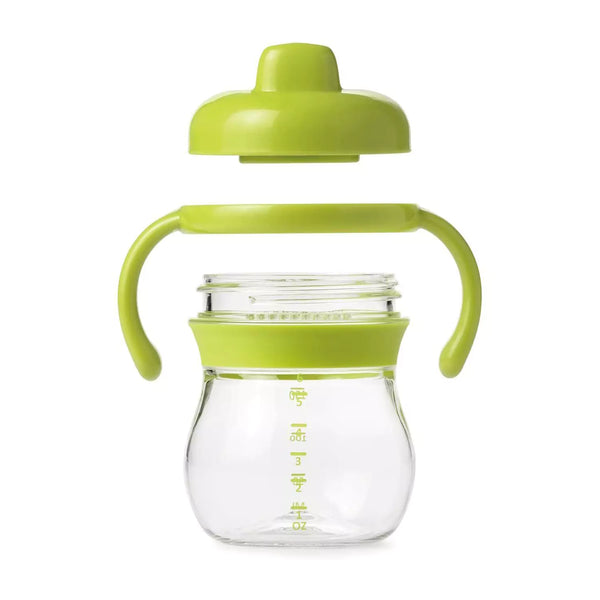 A green OXO Tot Transitions Hard Spout Sippy Cup with a soft spout and removable handles. The cup is made of BPA-free plastic and has a capacity of 175 ml.