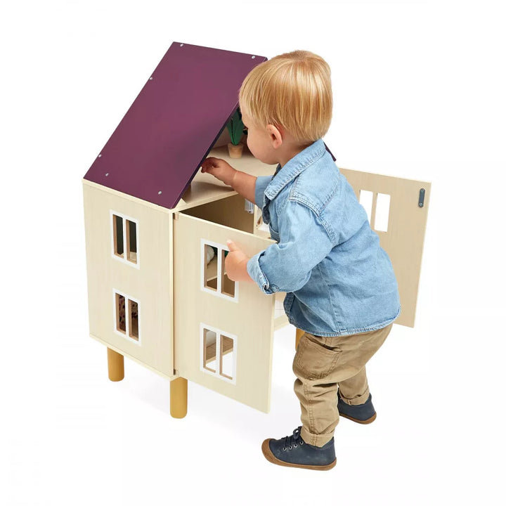 A boy playing with wooden dollhouse